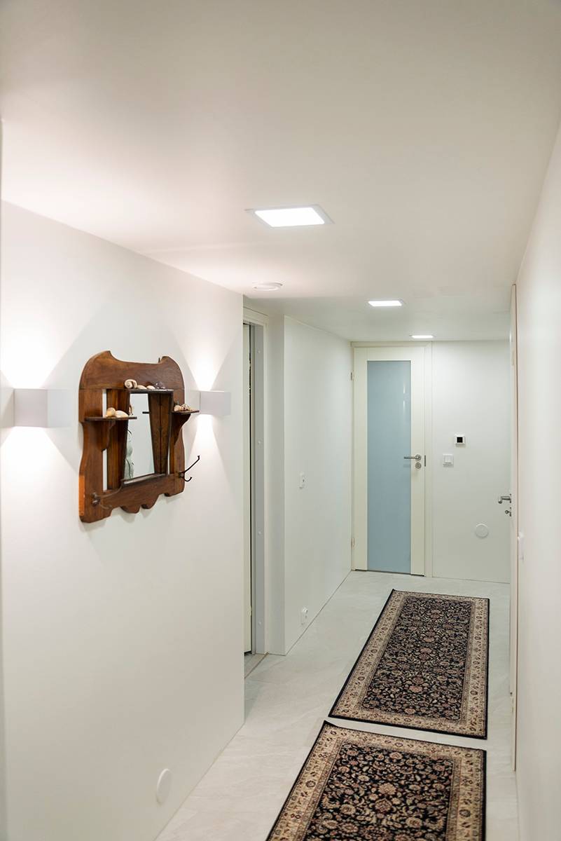 Apliques funk y paneles led empotrados en un pasillo blanco.
